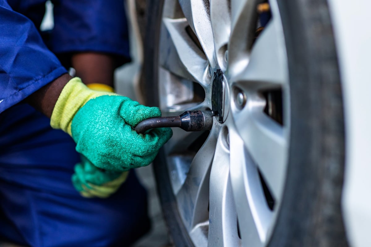 Borracheiro fazendo a troca de um pneu de carro no local